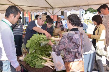 地域のまつりで、自作の野菜などを販売する塾生ら＝16日　山形・鶴岡市
